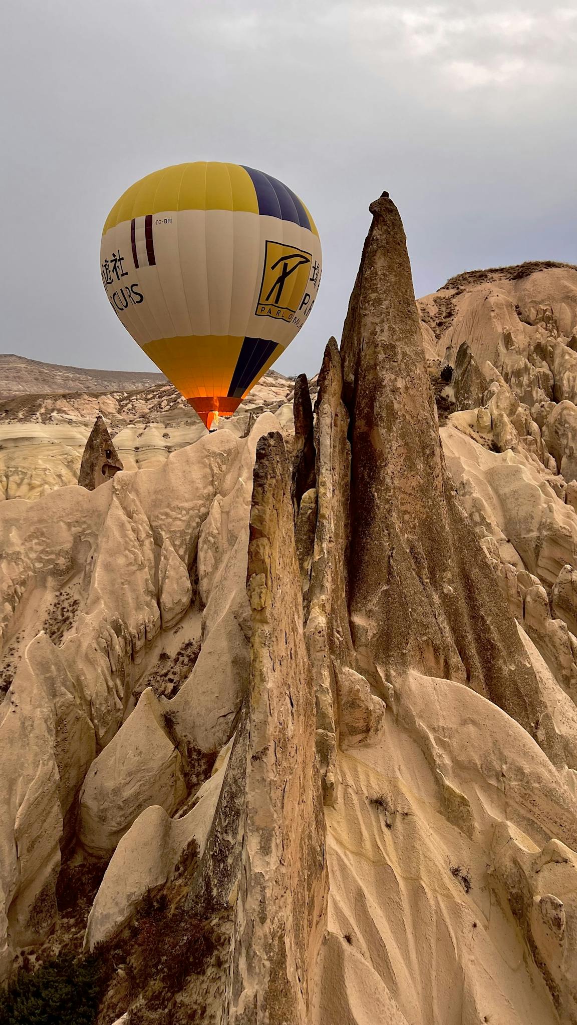 Hot air balloon soaring above Cappadocia's stunning rocky landscape, Turkey.